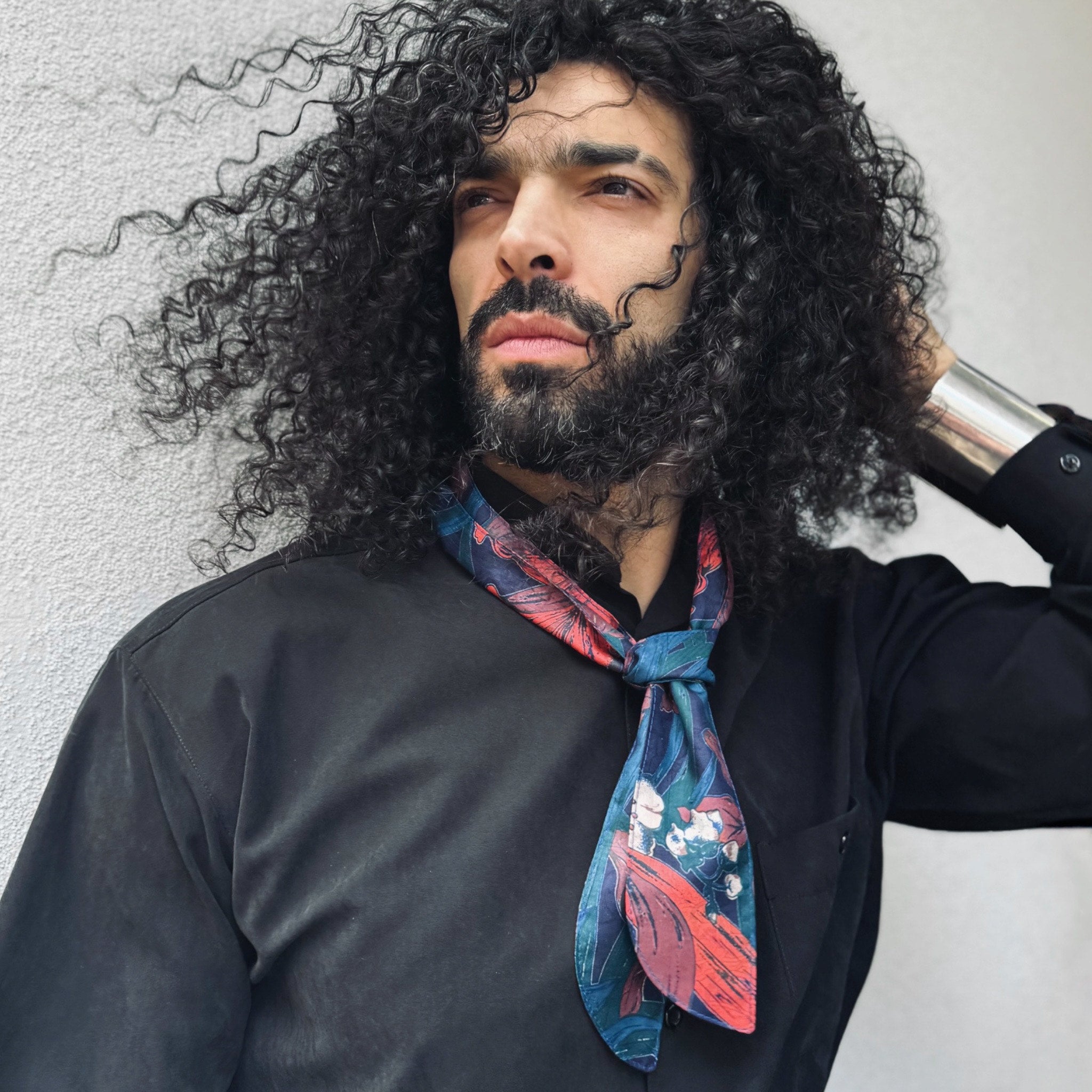Man with curly hair and beard wearing a colorful scarf